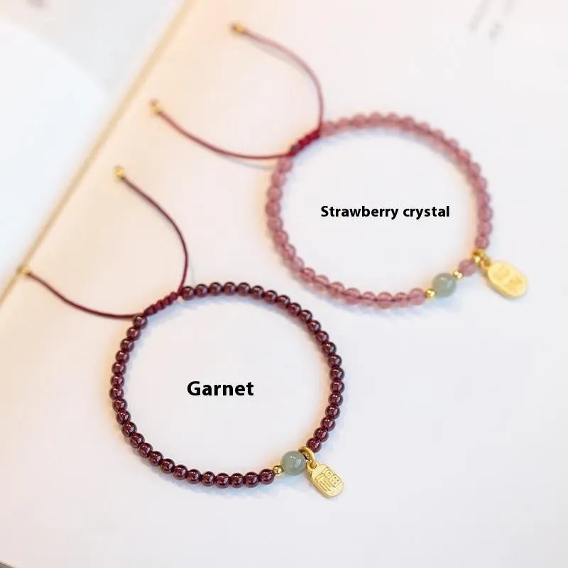 Hand-woven red rope bracelet with a strawberry quartz crystal charm on a wrist.