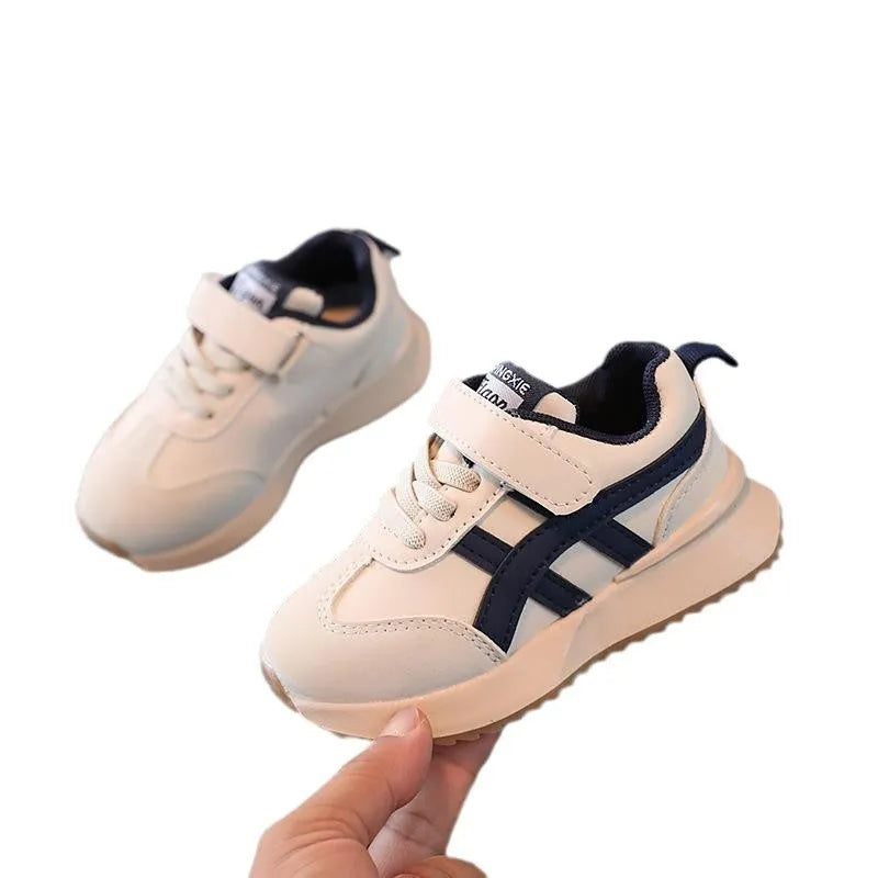 Children's solid-colour sneakers with Velcro strap in white, beige, or khaki on a rubber sole.