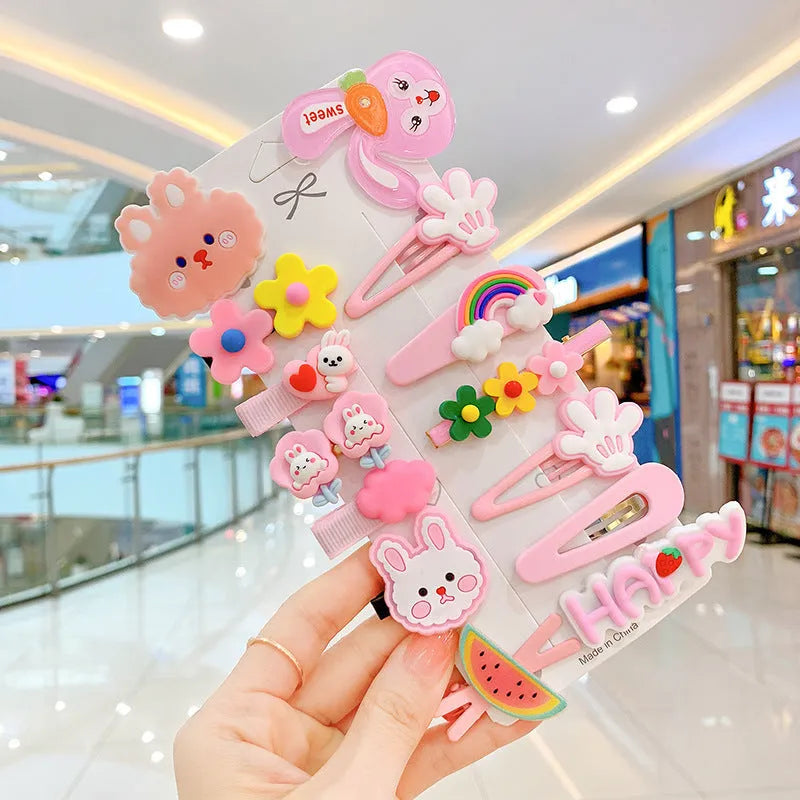 14-piece set of colourful toddler hair clips with candy, fruit, rainbow, and butterfly designs on a white background.