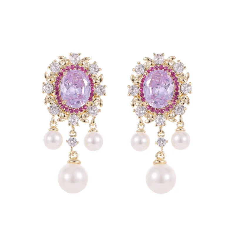 A pair of oval-shaped copper earrings with inlaid zircon stones and a dangling pearl tassel, shown in light purple.