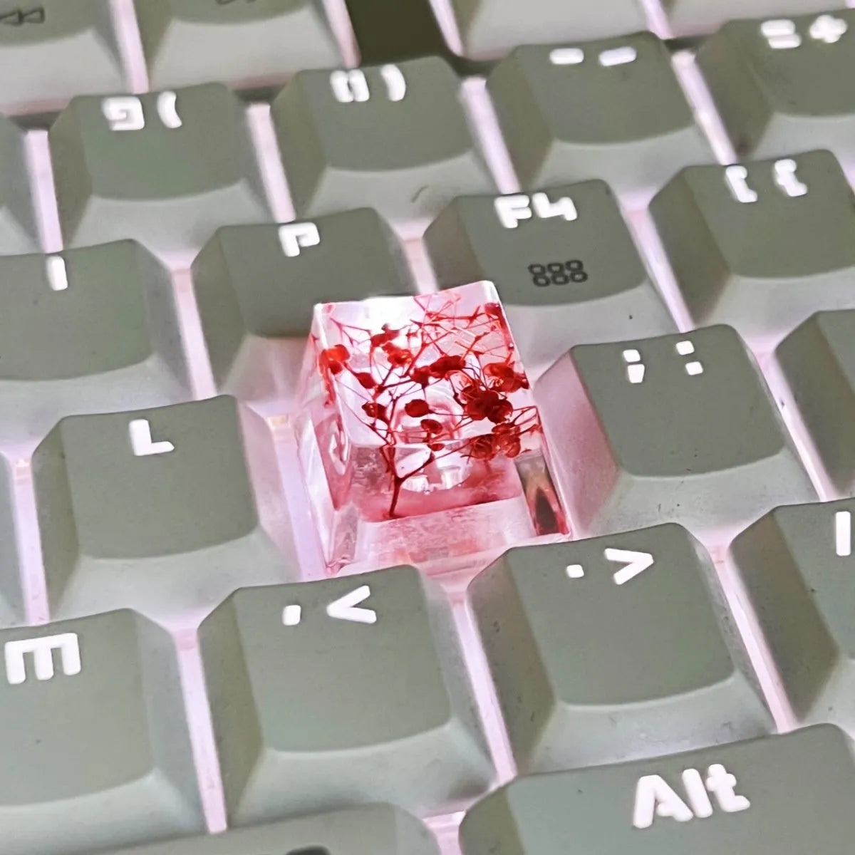 Transparent resin mechanical keyboard keycap with starry sky design in green, pink, red, violet colours.