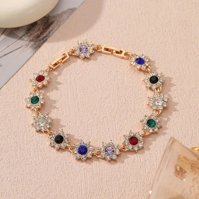 Floral shaped zinc alloy bracelet with electroplated silver finish and red coloured gemstones.
