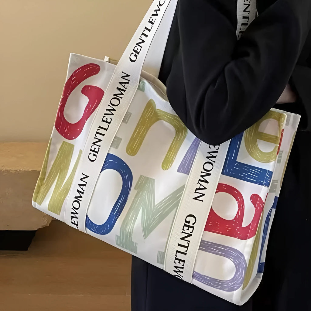 Large canvas tote bag with printed design showing black letters, available in multiple pattern options