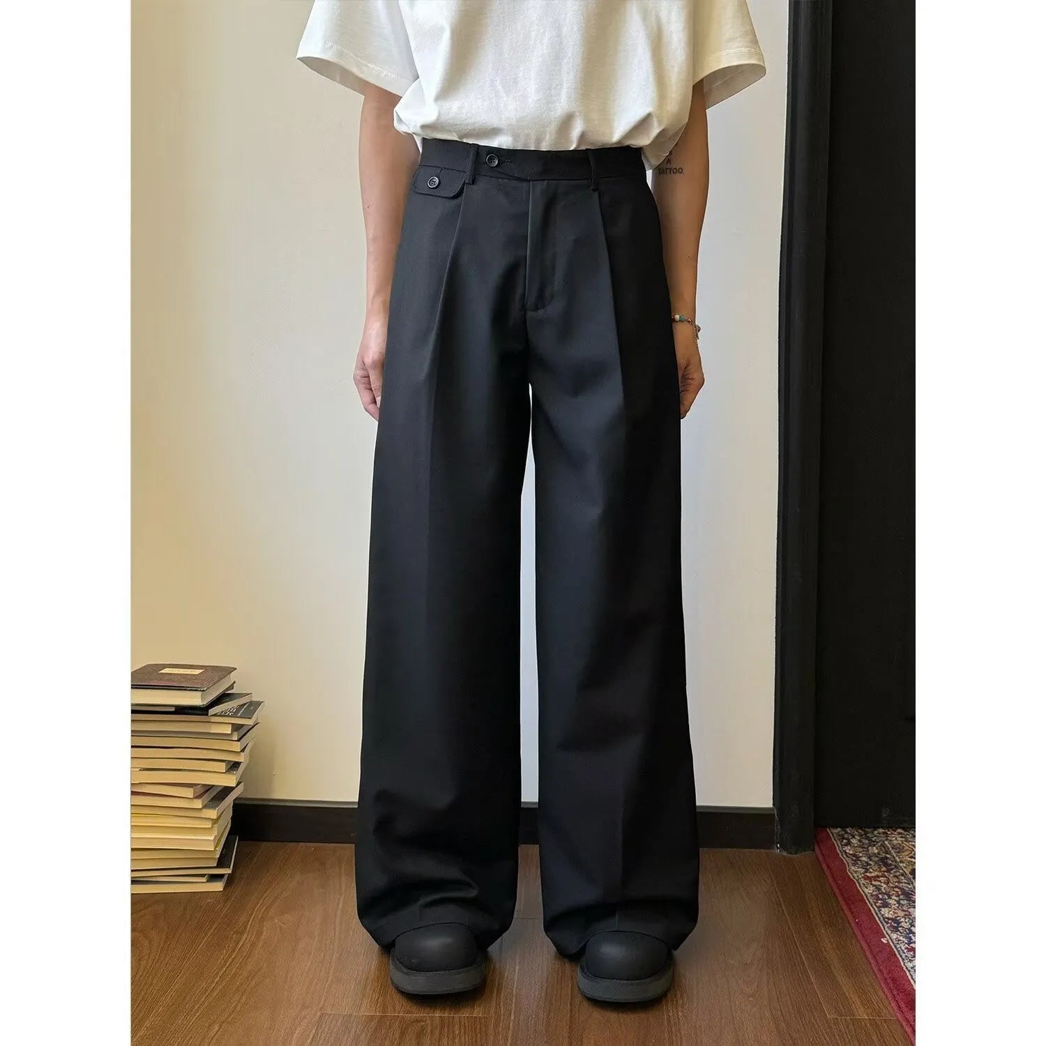 Men's straight-leg wide trousers in black, showing casual suit pant style with draping fabric.
