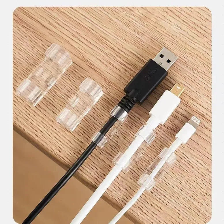 Transparent plastic self-adhesive cable clips for wire management on a desk.