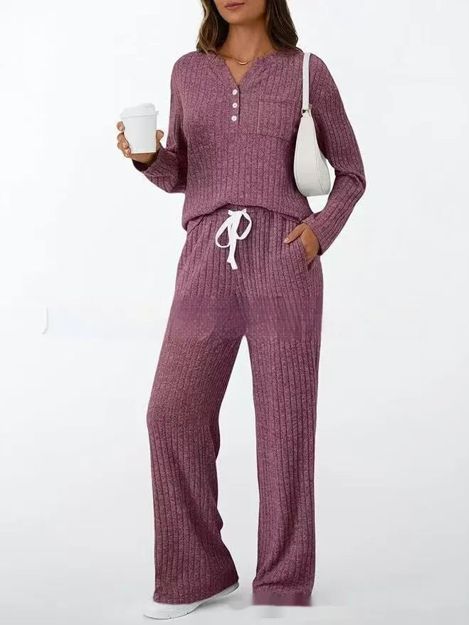 Woman wearing a striped knitted V-neck long coat with matching pants in a light grey colour.