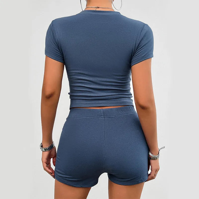 Women's solid colour slim-fit two-piece sports set with short-sleeved T-shirt and elastic waist shorts.