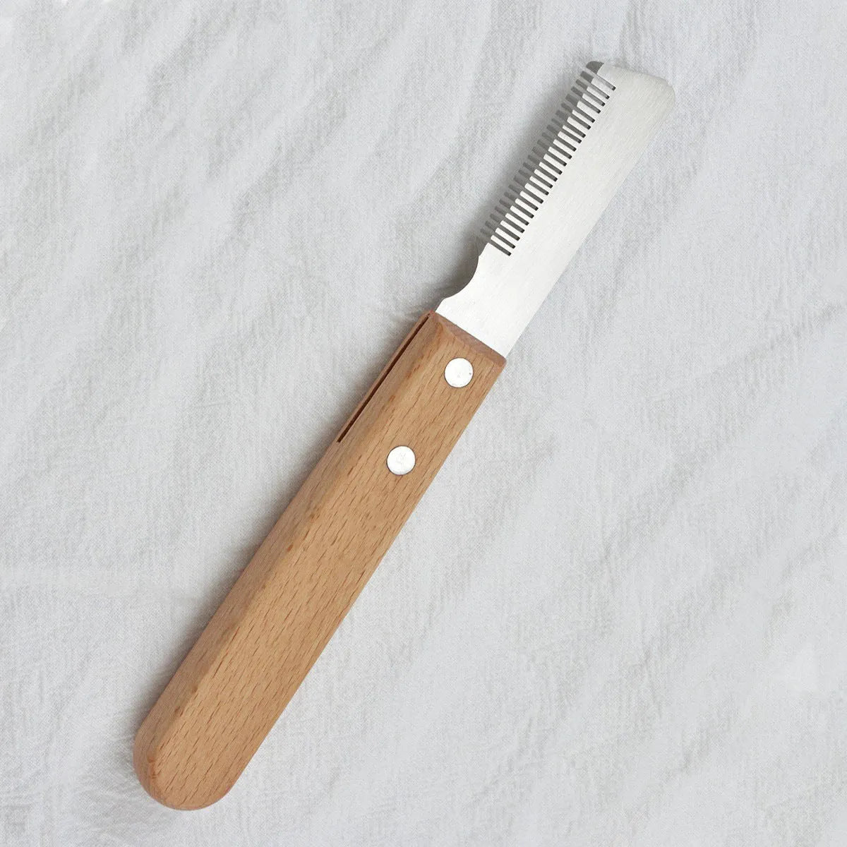 Wooden handled pet stripping comb grooming tool for dogs and cats on a table.
