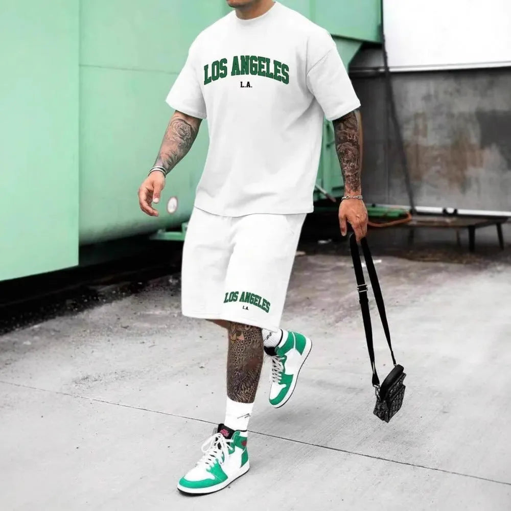 Man wearing a men's short sleeve top and shorts set with a 3D printed letter design, in a sportswear setting.