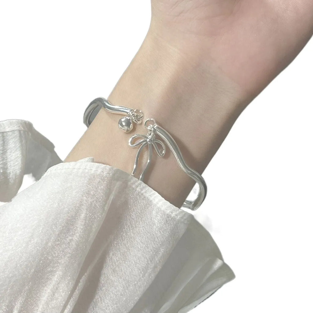 Silver bow adjustable bracelet with bow bell opening clasp on wrist