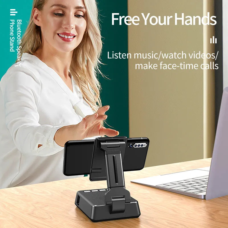 Black mobile phone broadcasting stand with integrated Bluetooth speaker on a desk.