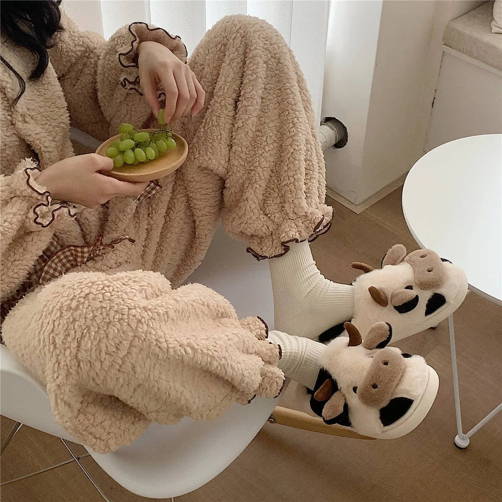 White plush cow-themed house slippers for women with a non-slip textured sole.