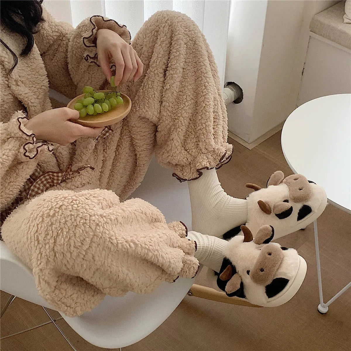 White plush cow-themed house slippers for women with a non-slip textured sole.