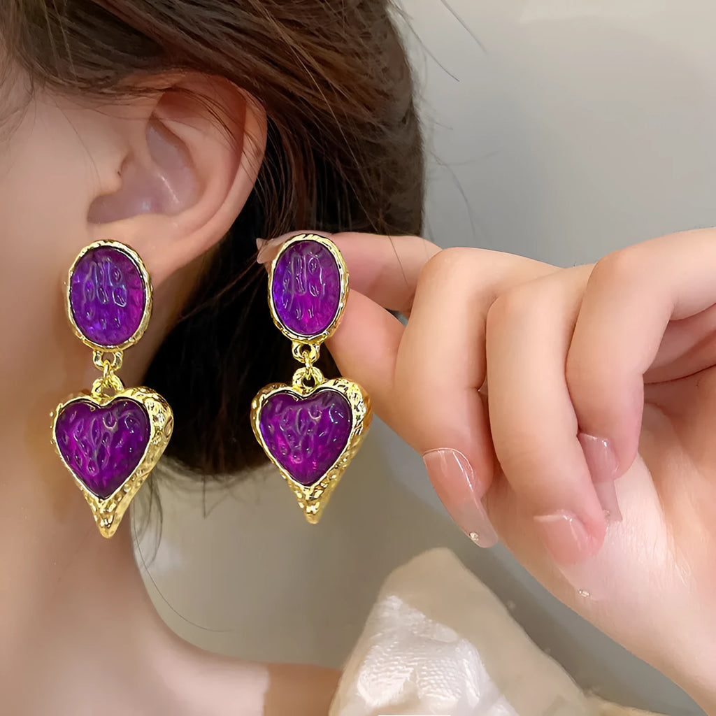 A pair of oval-shaped heart stud earrings with a silver needle texture in purple, red, green, and yellow white colours