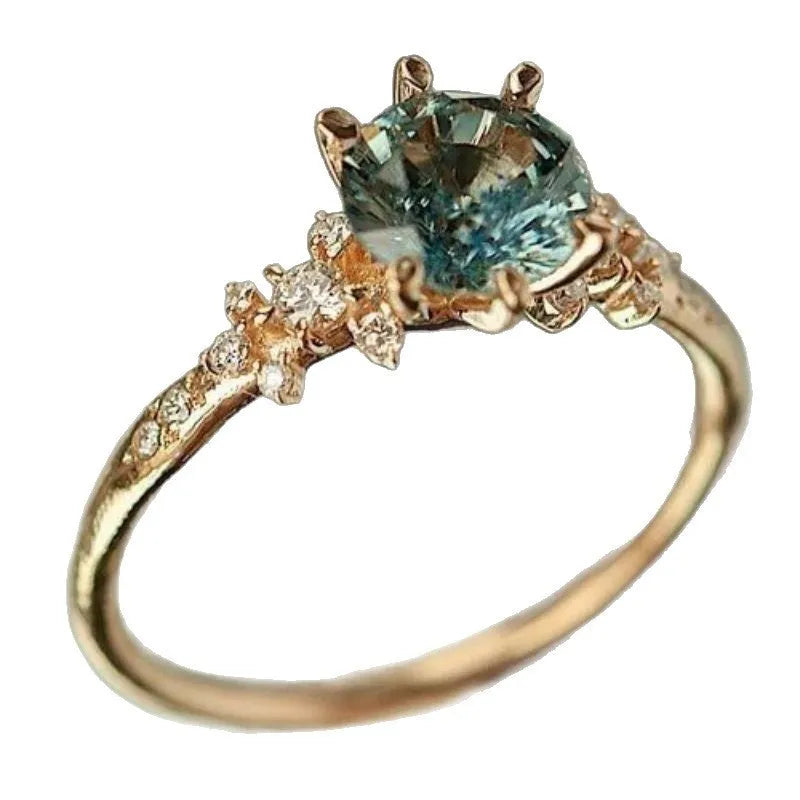 Gold geometric ring with a claw-set zircon stone and a chamfered square pattern design.