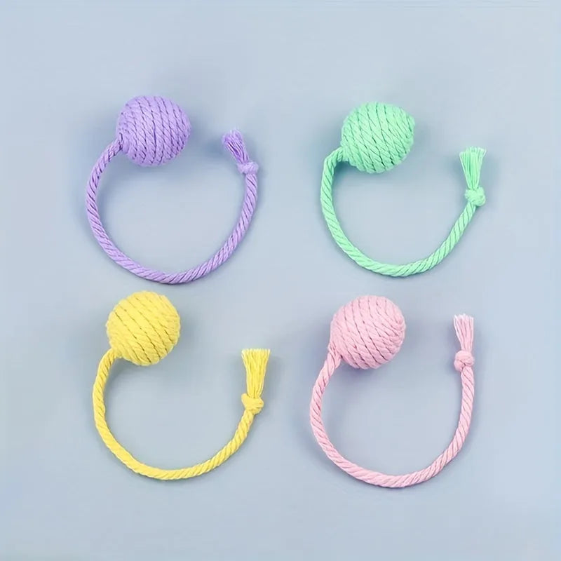 Green cat toy ball with attached rope on a wooden floor, shown next to a yellow 3cm size version.