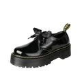 Women's white and black leather shoes with thick soles, ribbon and cross-strap design, and laced closure.