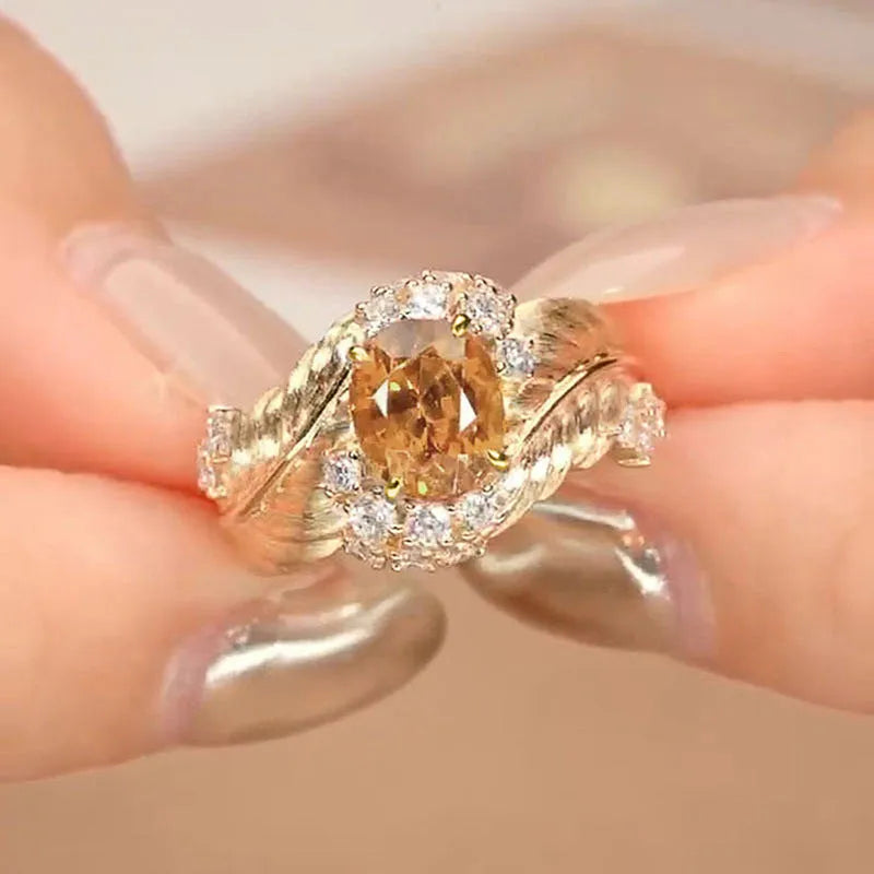 Gold-coloured embossed feather fashion ring with geometric shape and inlaid yellow zircon stones.